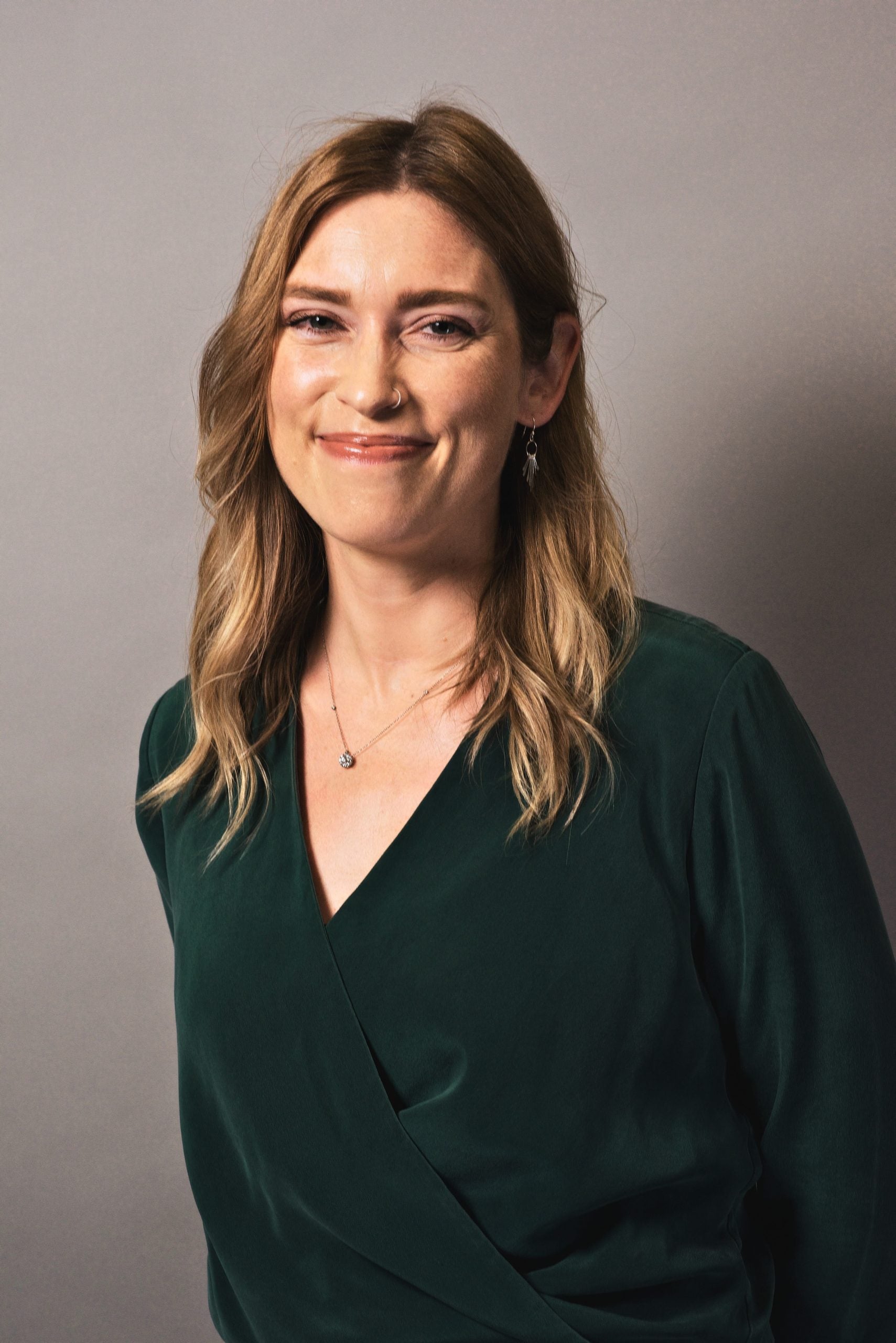 Headshot of Jenna Palensky in dark green blouse against a gray background